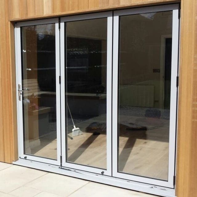 Aluminium bifold doors opening from a contemporary kitchen onto a cedar-clad garden room