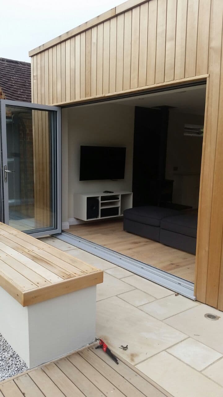 Schuco aluminium bifold doors fully open connecting a living room to a garden