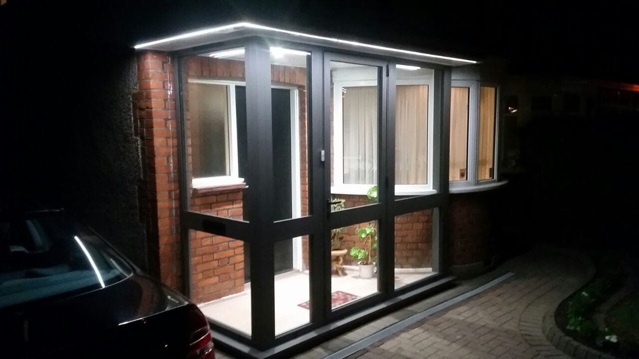 Aluminium porch with Crittall-style glazing illuminated at night