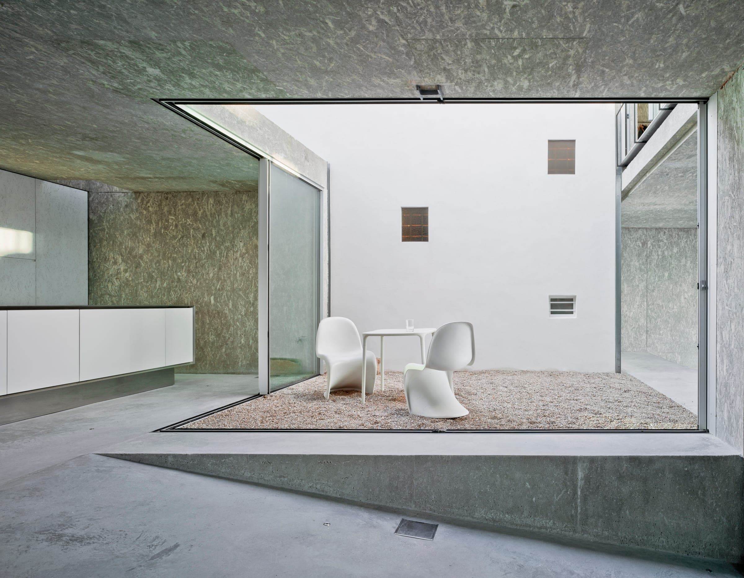 Cortizo minimal sliding door opening to courtyard with Panton chairs