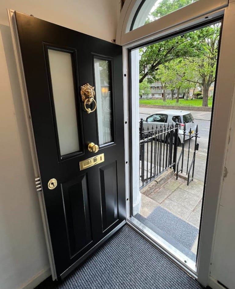 Reinforced steel front door with gold lion-knocker, installed on a residential property