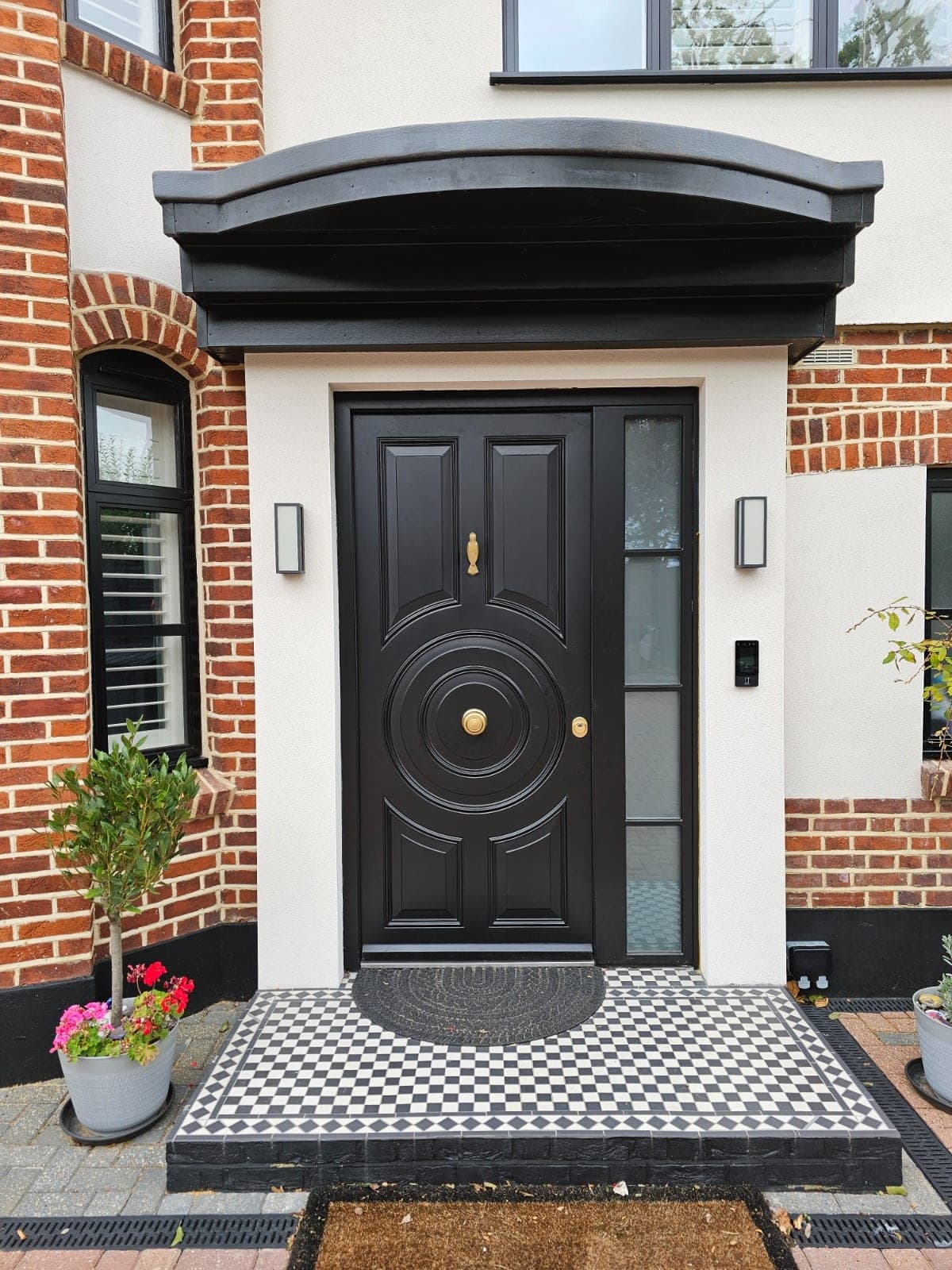 Black steel front door with ornate detailing installed on a UK home with chequered tile porch