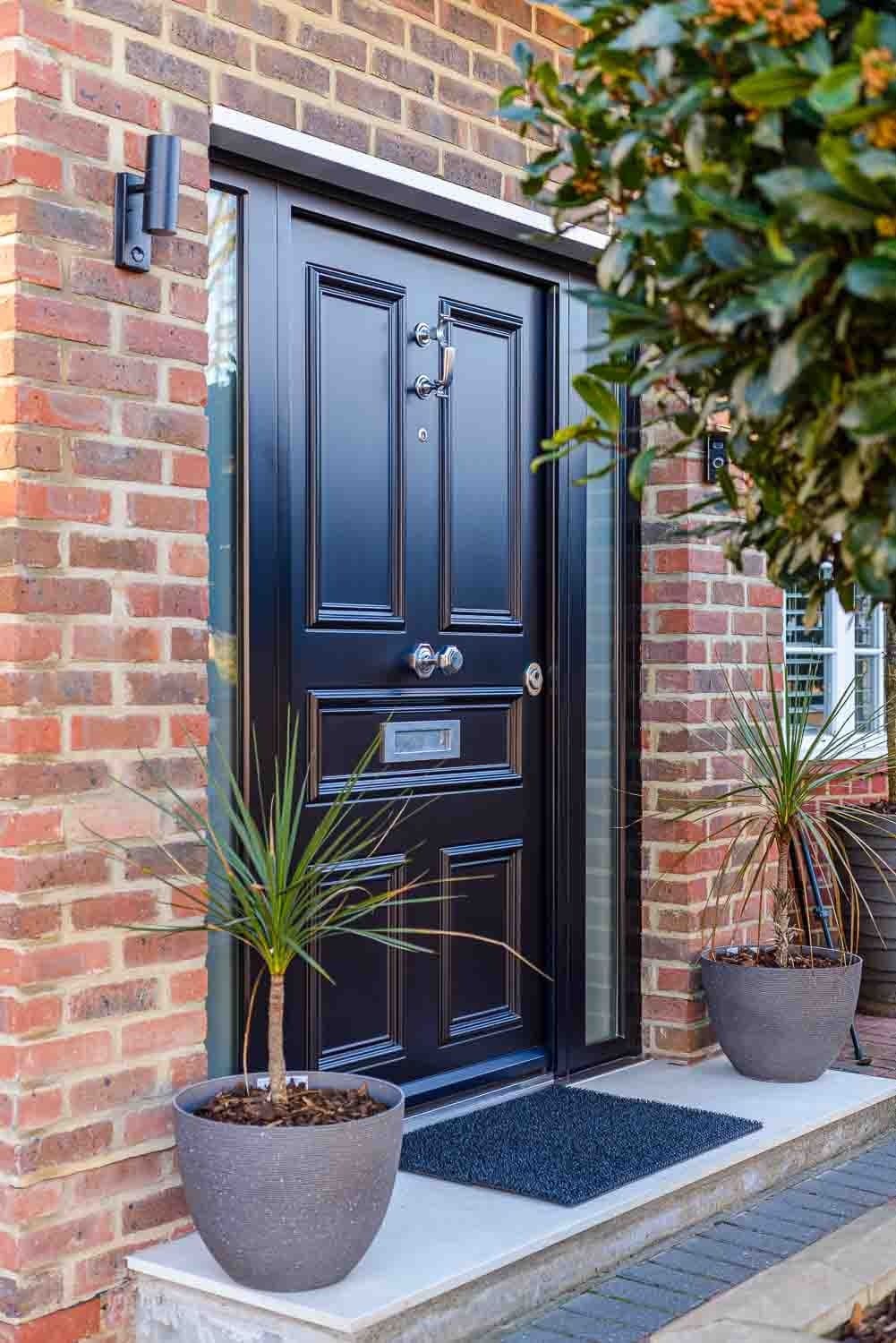 SteelR navy panelled steel door with chrome hardware and palm plants
