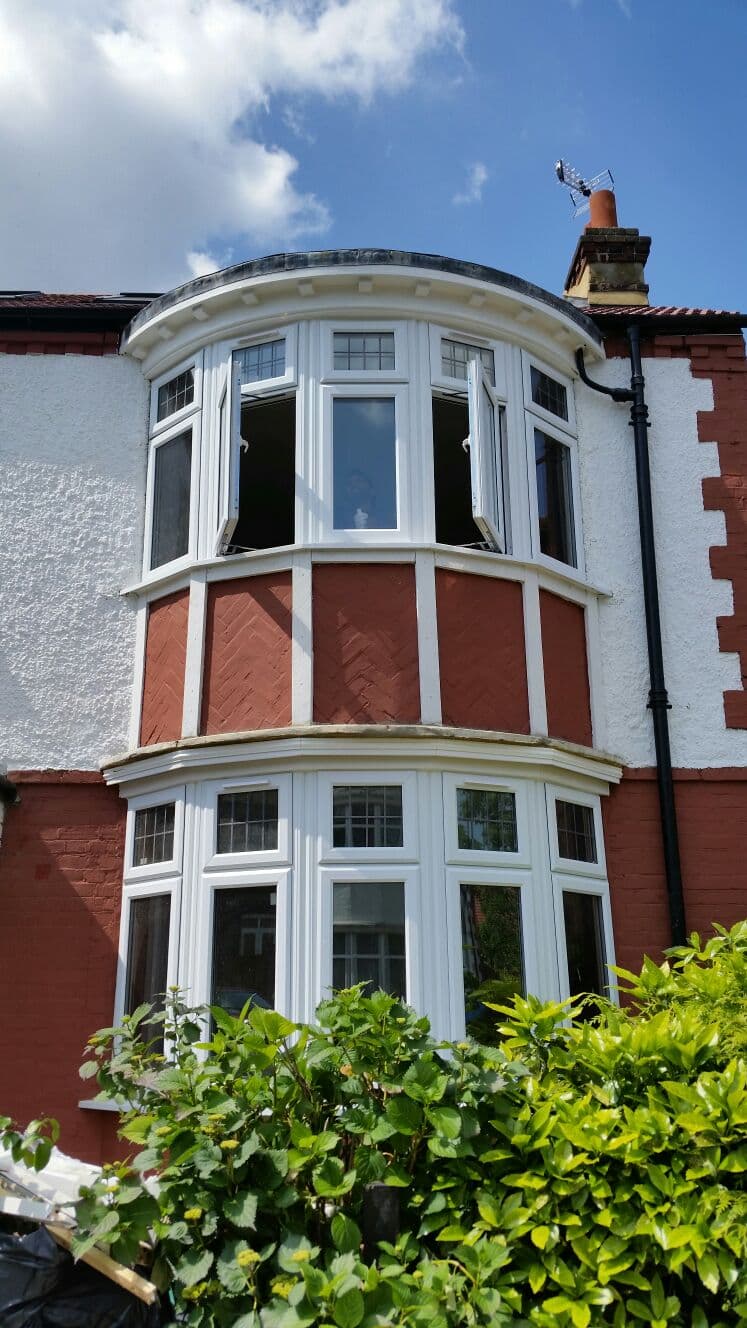 Double-height curved bay windows on period red brick home