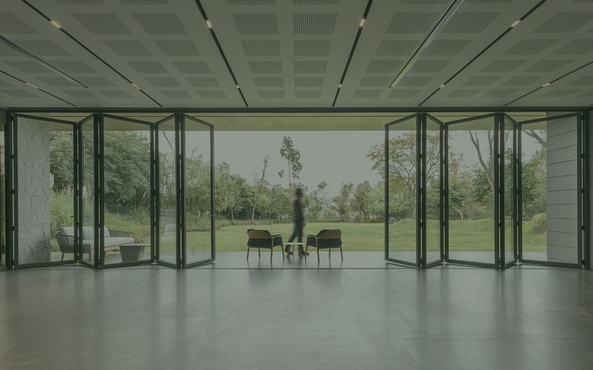 Thermally broken aluminium bifold doors open onto a UK garden, illustrating a warm, well-sealed winter installation
