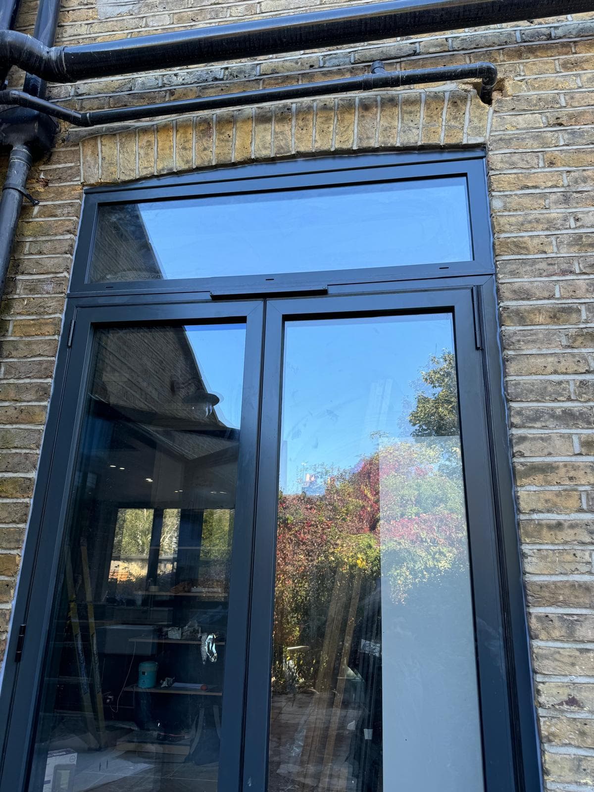 Aluminium French doors opening onto a garden from a modern extension, slim black frames with full-height glazing