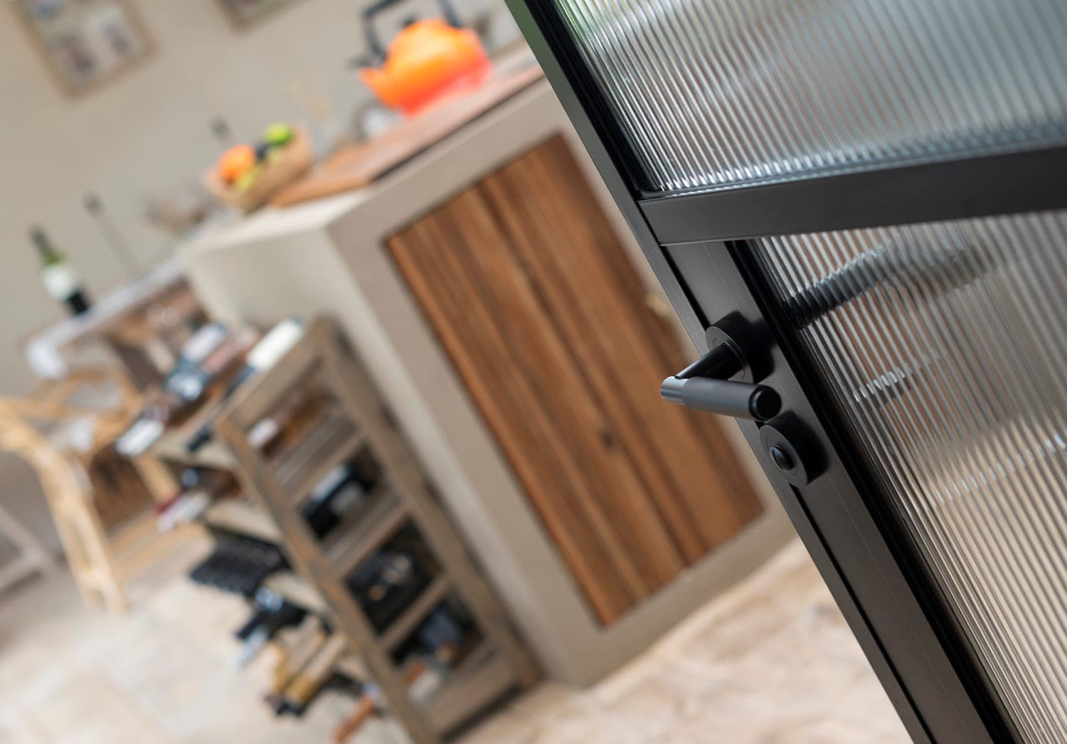 Origin OI-30 aluminium internal door framing a view onto a kitchen island with bar stools and wooden cabinetry