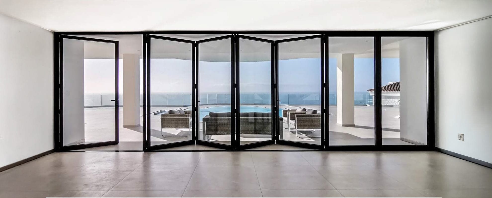 Cortizo aluminium bifold doors opening to a sea-view terrace, 7 panels, anthracite frames
