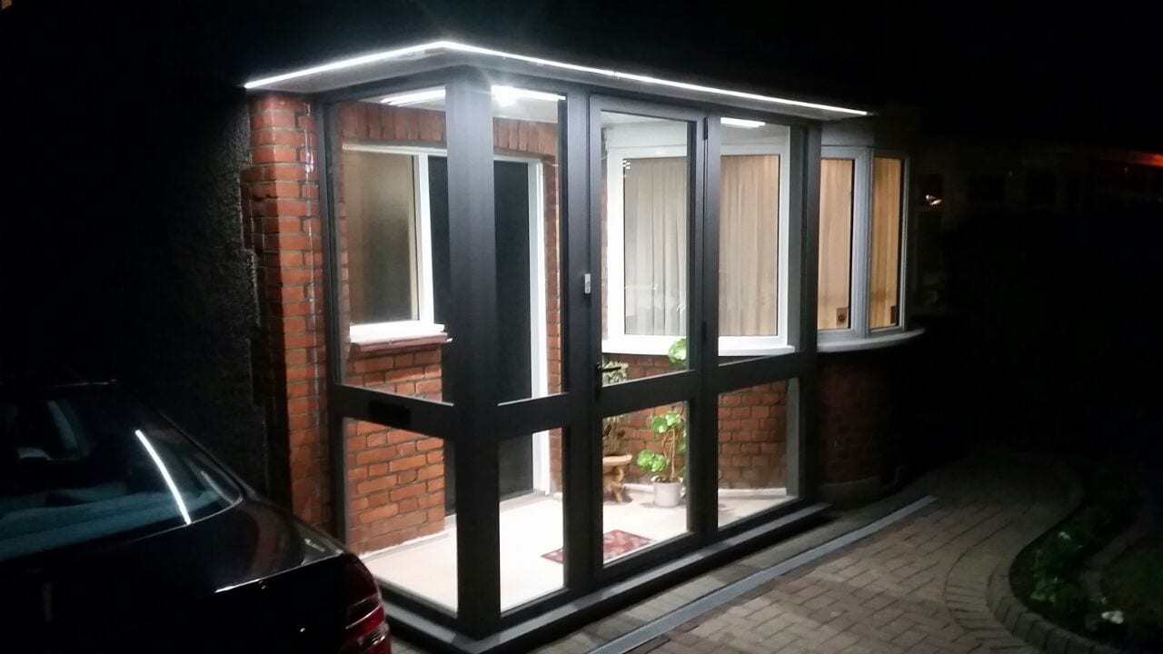 Aluminium porch with Crittall-style glazing illuminated at night